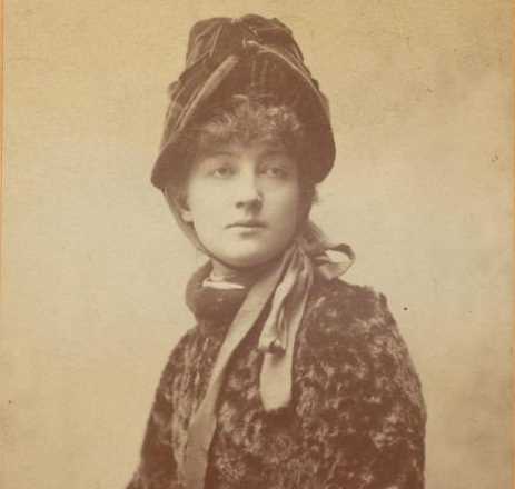 Dagny Juel in a half-length sepia-toned photograph. She is wearing a hat tied under her chin and a fur coat. Photograph.