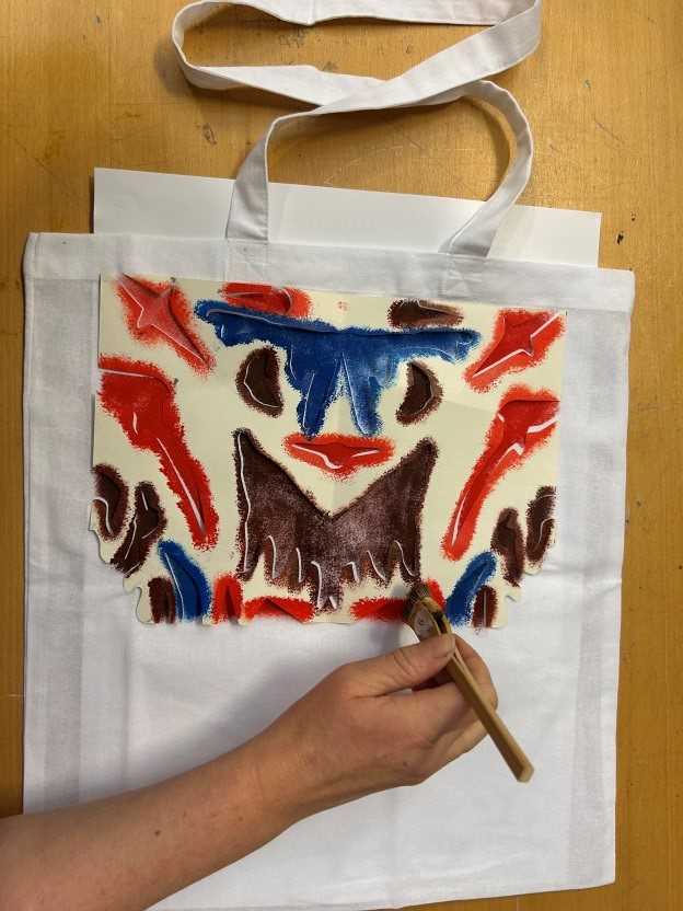 Hånd som maler med pensel på en totebag.