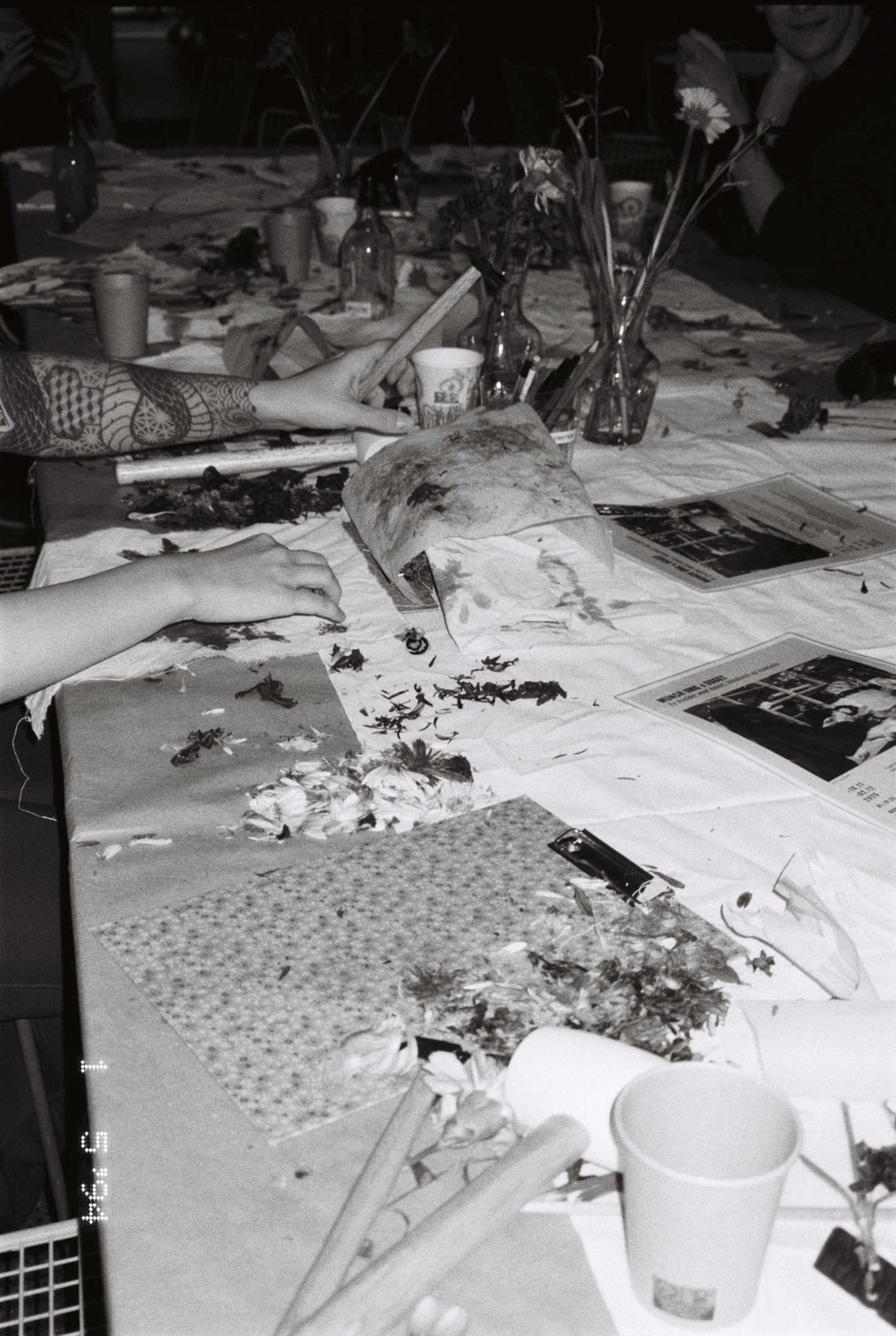 Et verkstedbord der flere mennesker sitter og lager håndarbeid. Fotografi