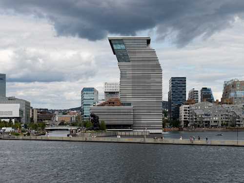 MUNCH sett fra Sørenga. I forkant ser du to mennesker som padler kajakk og bak dem en gangbro som ligger på vannet. Himmelen er blågrå og skyet. Fotografi