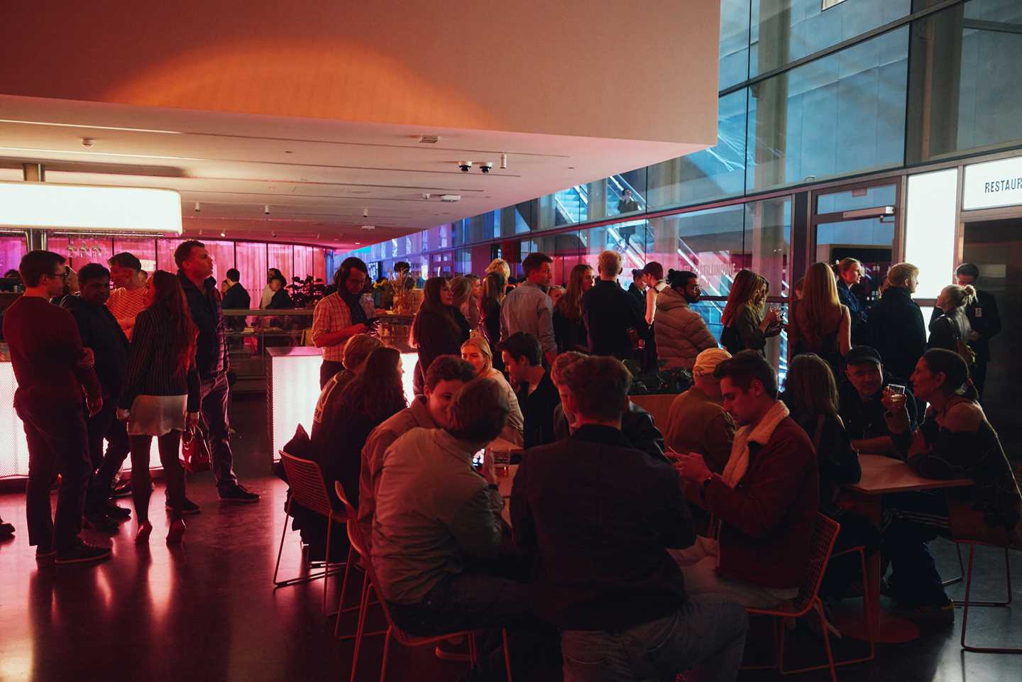 Lobbybaren på MUNCH full av mennesker som sitter og står mens de prater, danser og står i kø. Fotografi