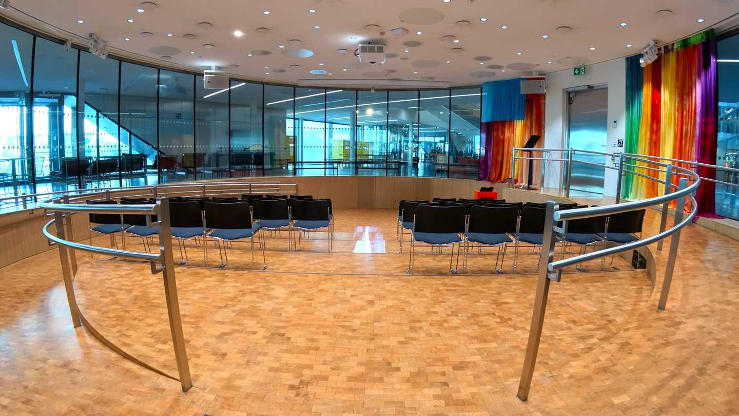 Amfi-salen på MUNCH. Et rundt rom med vinduer rundt hele rommet. I midten av rommet er det fire stolrader. Fotografi