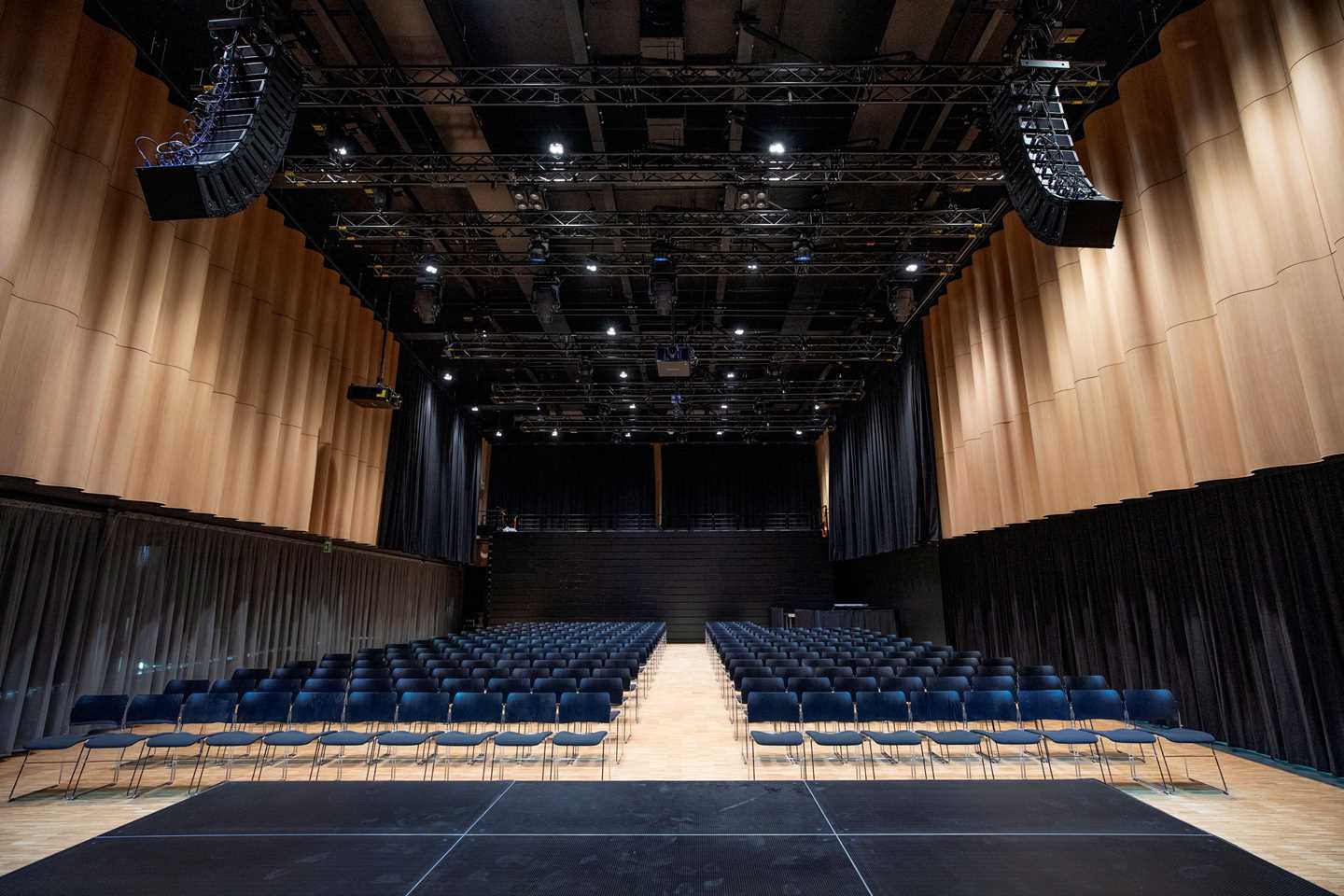 Festsalen på MUNCH fra scenen. I taket er det en stor lyd- og lysrigg. På gulvet står det mange stolrader med svarte stoler vendt mot scenen. Fotografi