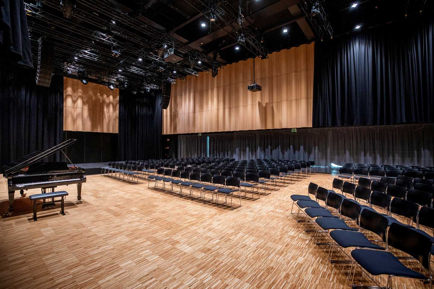 MUNCHs festsal rigget med et flygel og grupperinger av stolrader på tre kanter. Fotografi