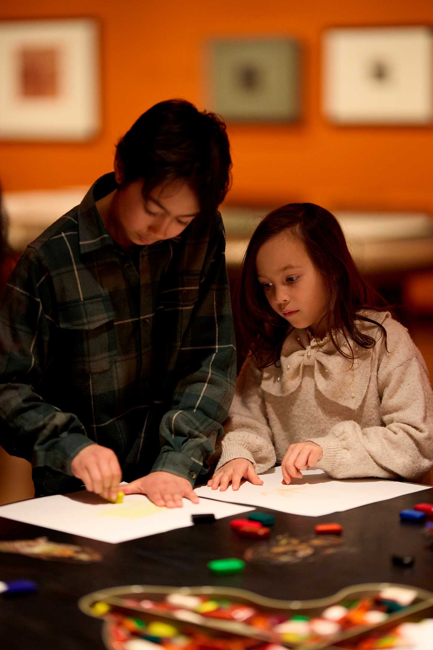 To barn tegner ved et tegnebord i utstillingen Inntil. Fotografi