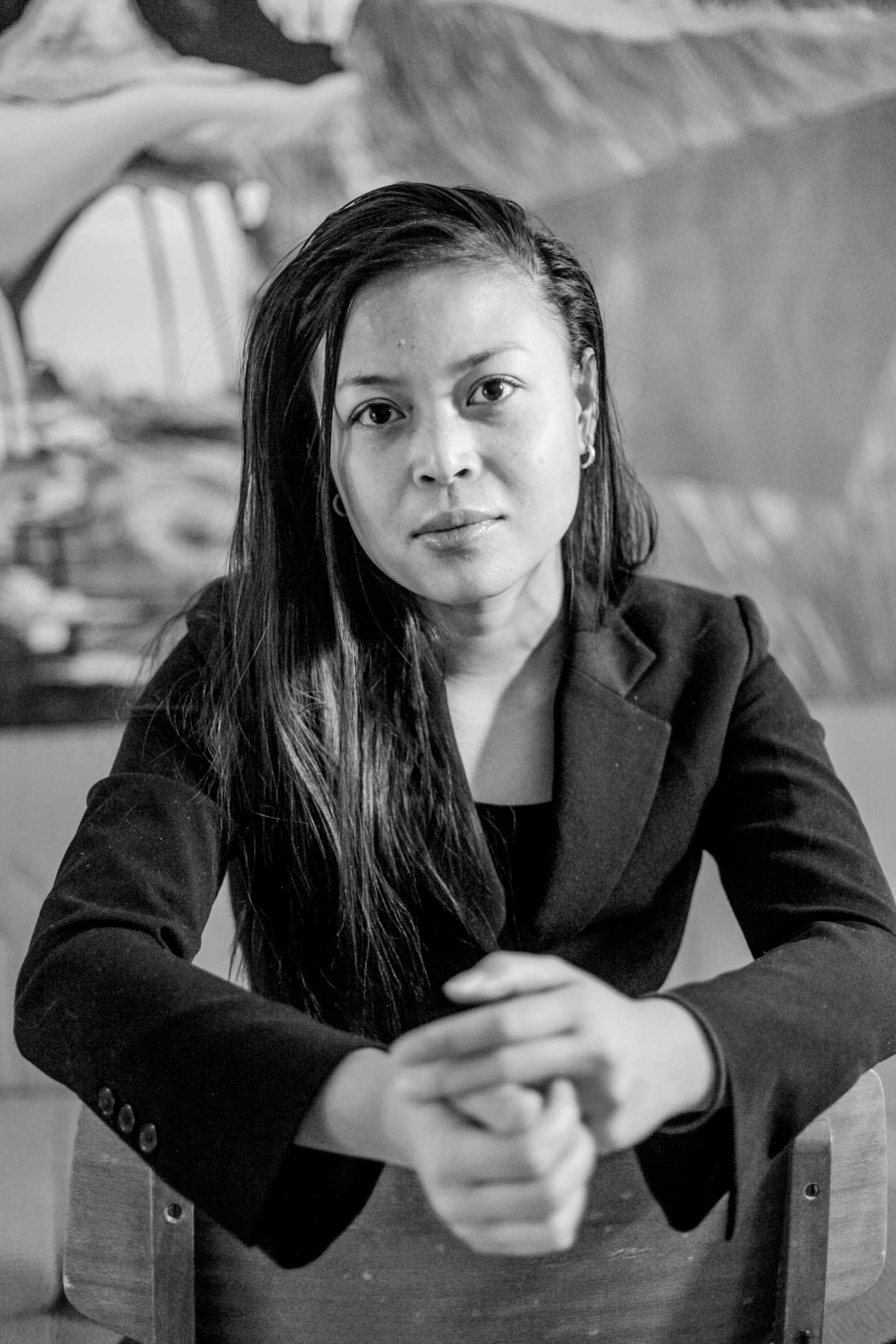 Svart hvitt- foto av en kvinne med lang svart hår og blikket rett fram. Hendene er foldet.