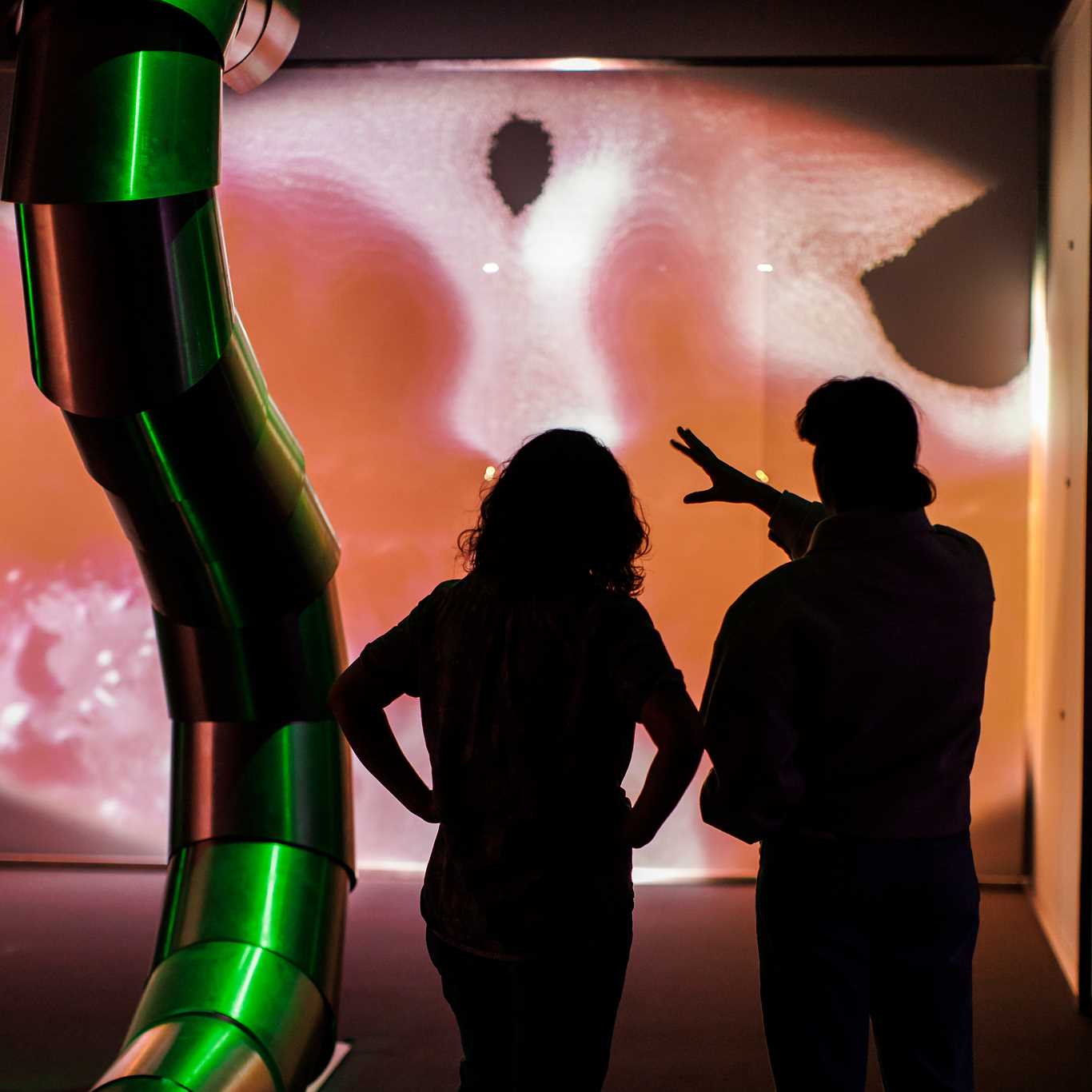 To mennesker står i en utstillingssal og ser på kunst av Sandra Mujinga. Vi ser de bakfra. Fotografi