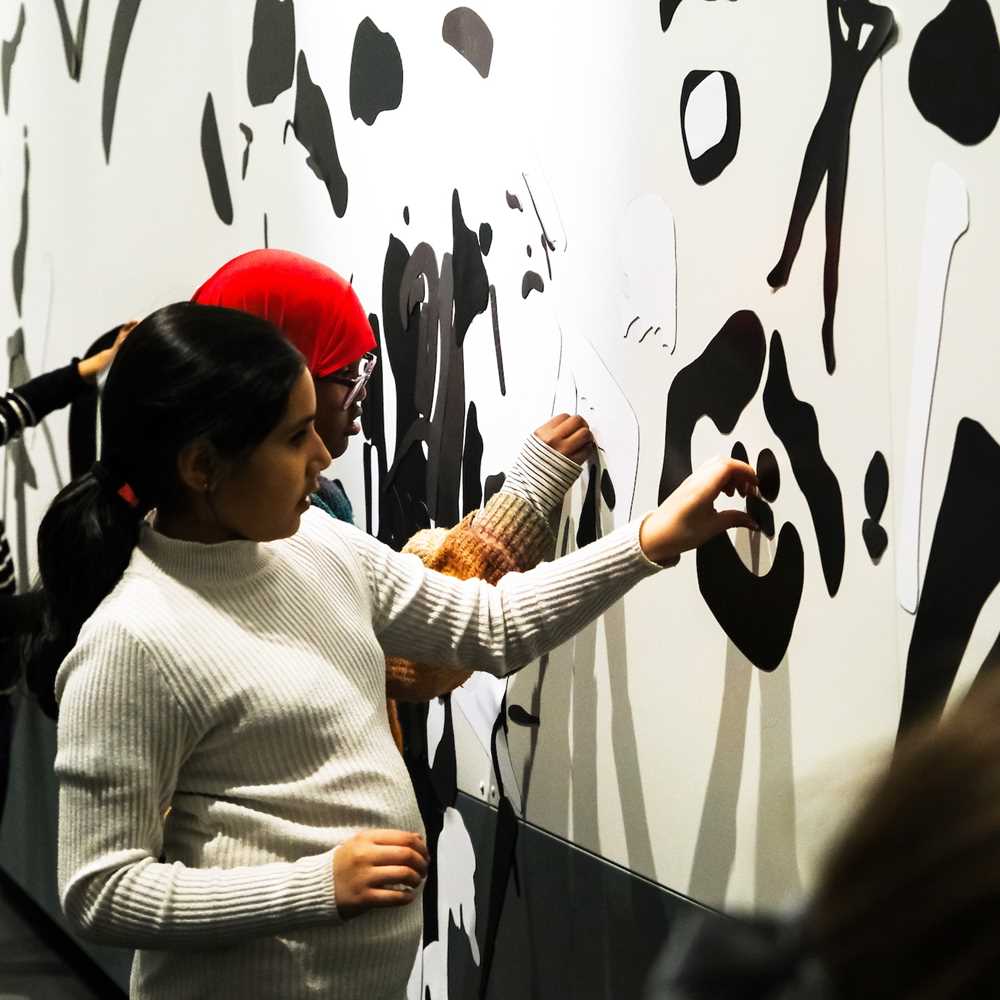 Fire barn som fester svarte magneter på en hvit vegg. Foto