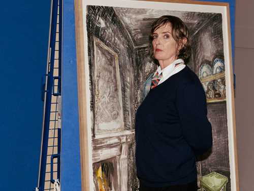 Vanessa Baird står i halvprofil foran ett av sine egne verk og vrir hodet mot kamea.