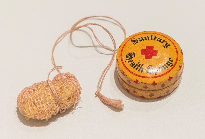 En gammel sanitærsvamp med tilhørende etui i metall.