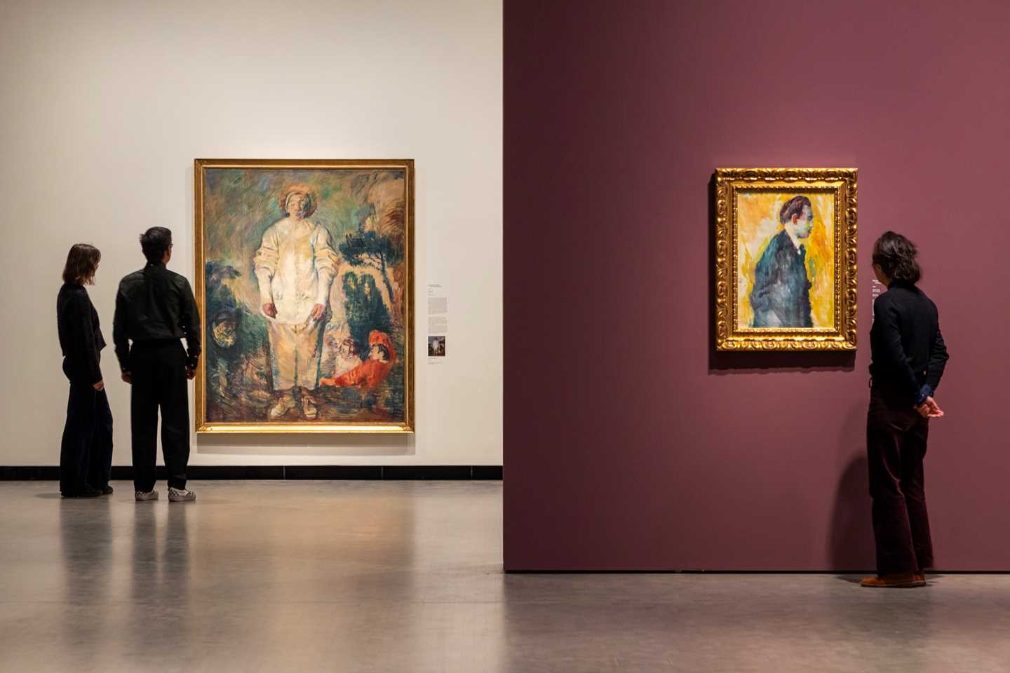 Bilde fra utstillingssal som viser tre personer som ser på to ulike verk av Ludvig Karsten. Fotografi
