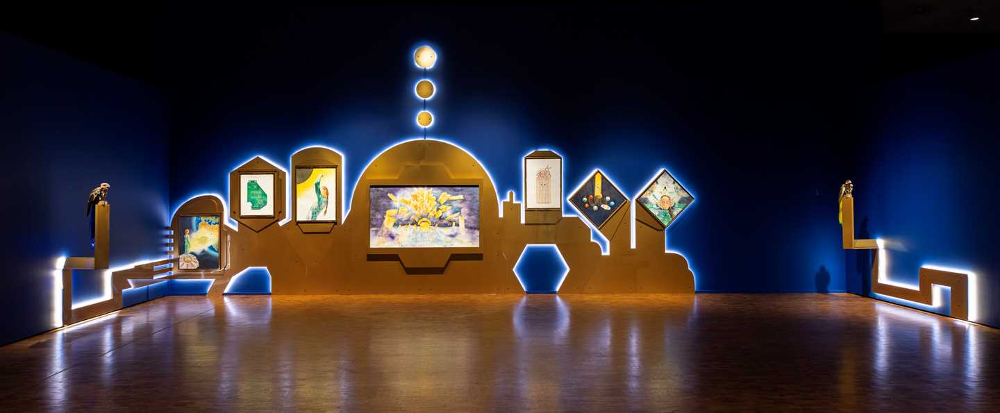 Installation view of the work by Patricia Domínguez, consisting of many watercolours, with two birds with red eyes perched as guardians at each end of the installation. Photograph.