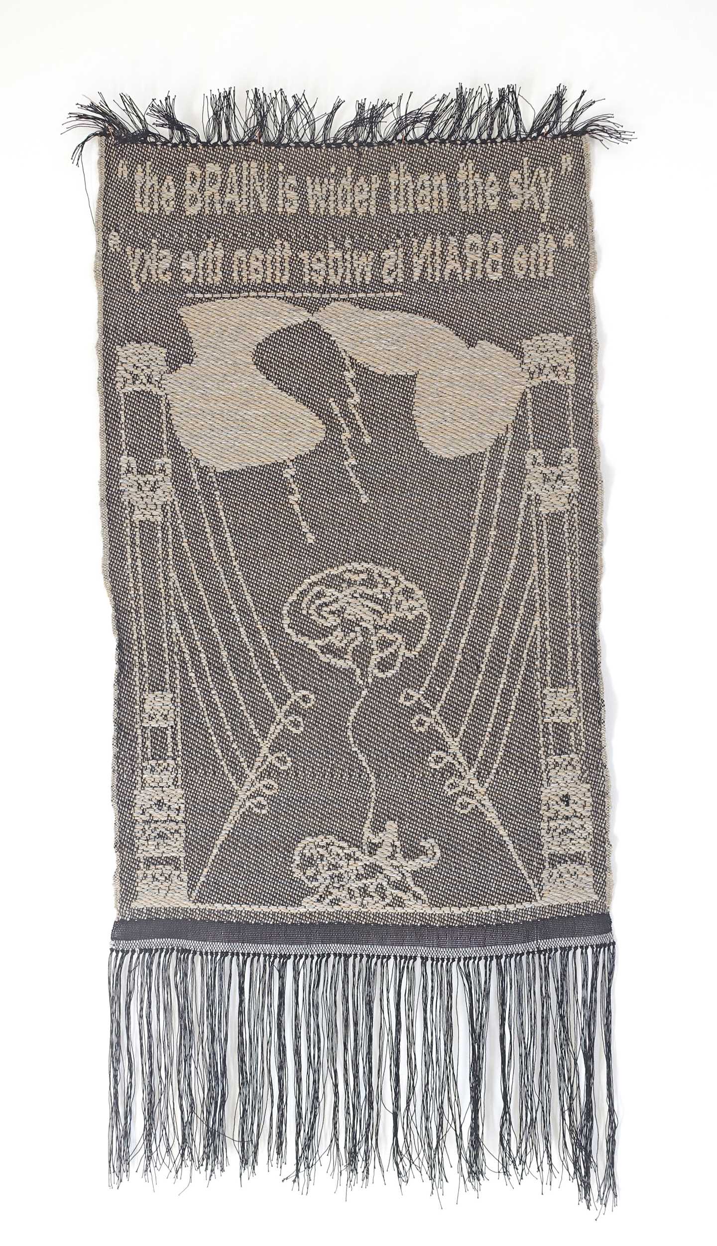 En billedvev i gråtoner med teksten The BRAIN is wider than the sky. I midten av veven er en hjerne og over den skylignende former som det kommer lyn ned fra. Fotografi