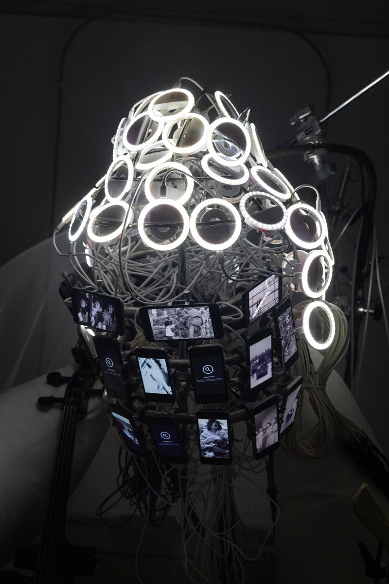 Circles of white LED lights, wires, and mobile phone screens are assembled into the shape of a Buddha head. This is a close-up of part of the installation. Photograph.