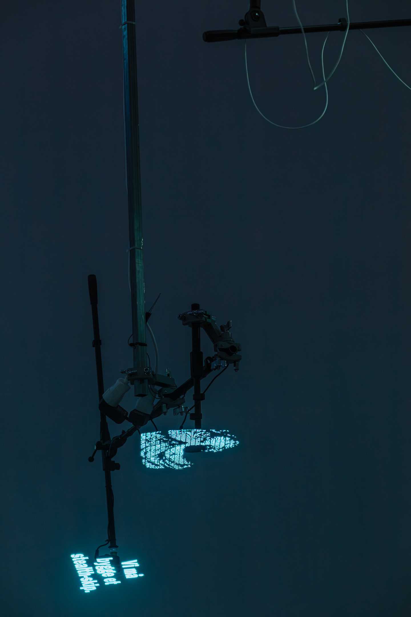 Fans hang from the ceiling, displaying text and waves as holograms. Photograph.
