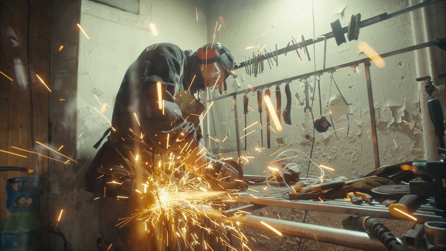 Artist Kim Hankyul cutting metal, standing amid a shower of sparks. Photograph.