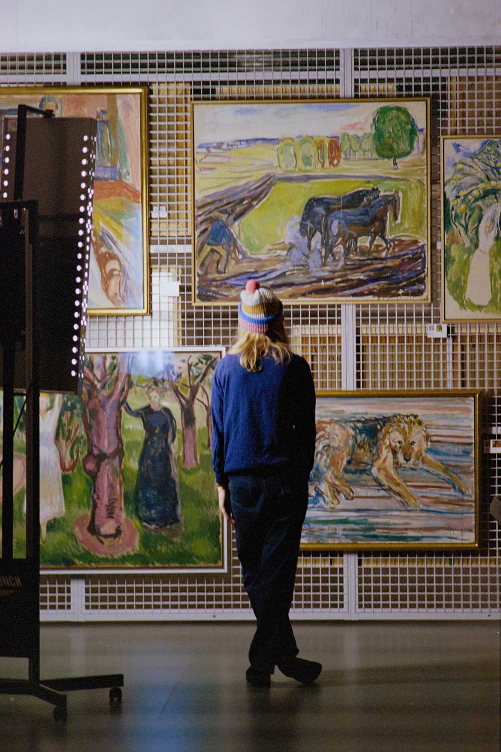 Artist Marie Ulven står med ryggen mot kamera foran flere verk av Edvard Munch. Fotografi