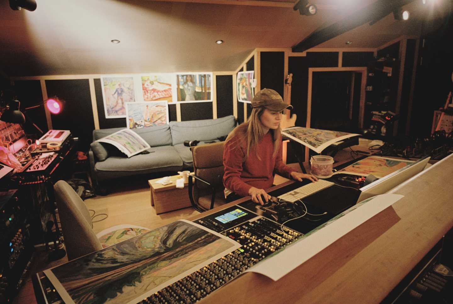 Artist Marie Ulven sitter ved miksepulten i sitt eget studio. På veggen bak henne henger det plakater med verk av Edvard Munch. Fotografi