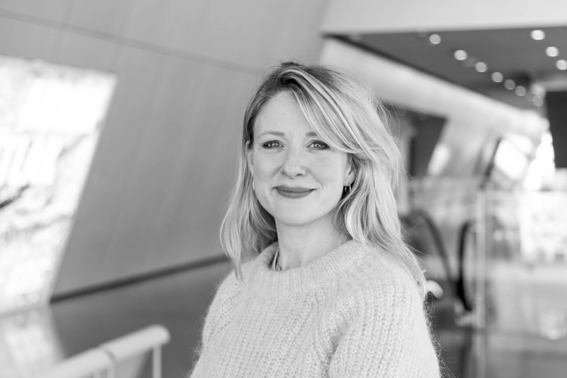 Sort hvitt bilde av kvinne med blondt hår og strikket genser.