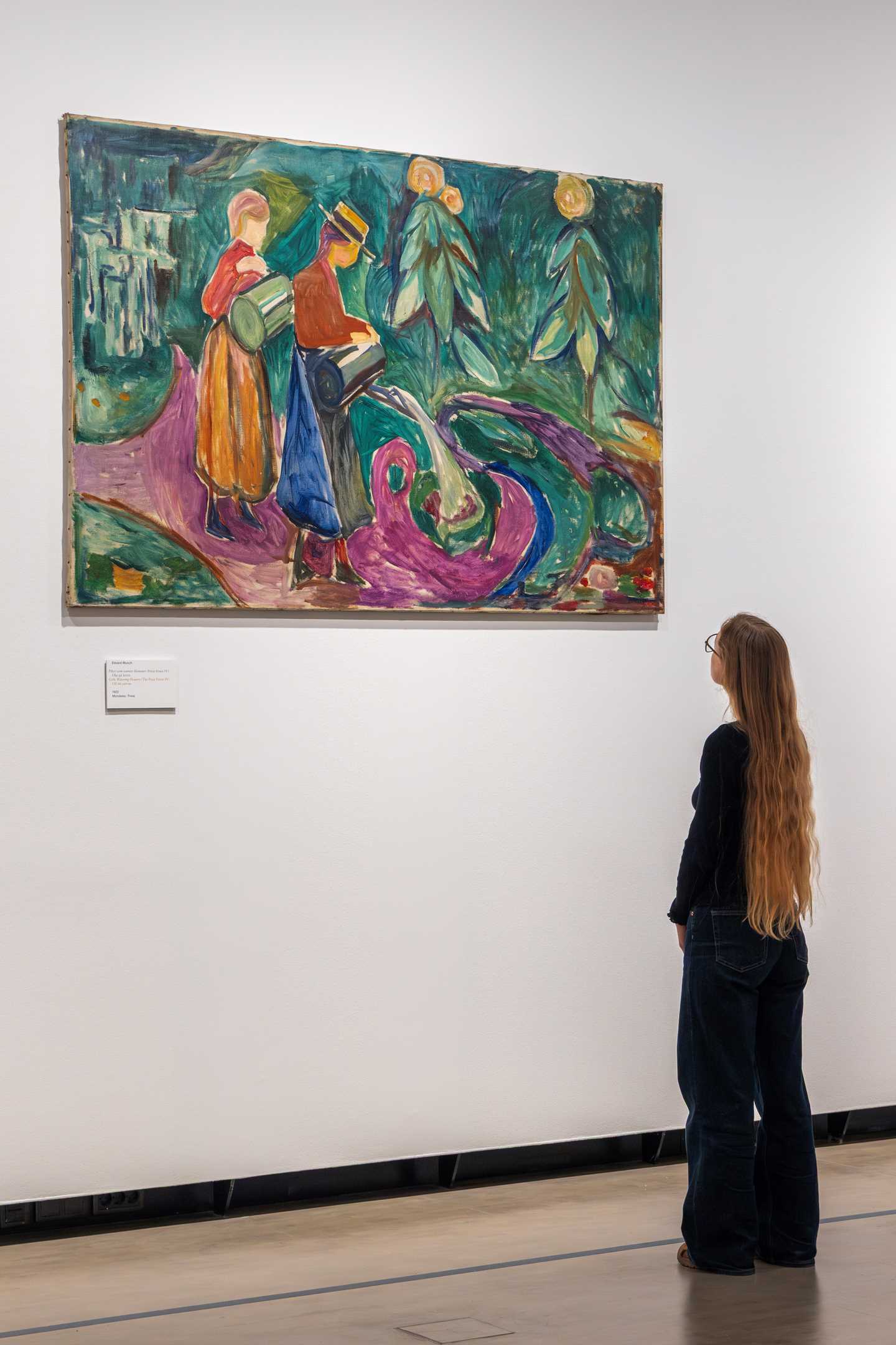En kvinne med langt hår betrakter verket "Piker vanner blomster" av Edvard Munch.