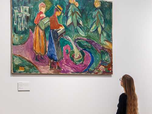 En kvinne med langt hår betrakter verket "Piker vanner blomster" av Edvard Munch.