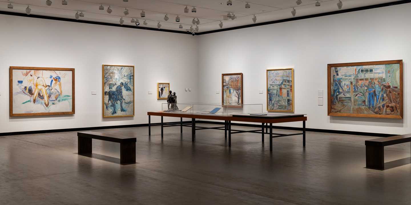Oversiktsbilde fra utstillingssal som viser flere malerier med arbeidermotiver av Edvard Munch. Fotografi