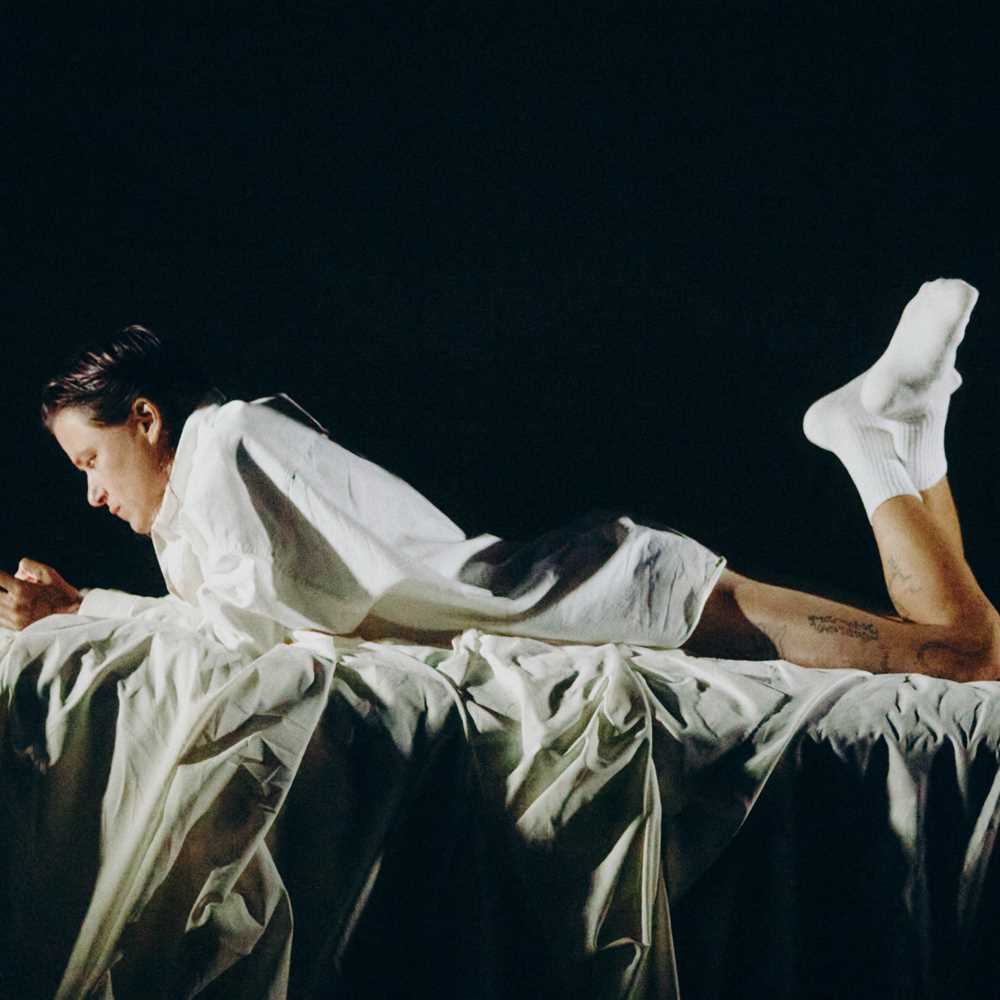 Foto av person som ligger på magen og ser på en mobiltelefon, med sort bakgrunn.